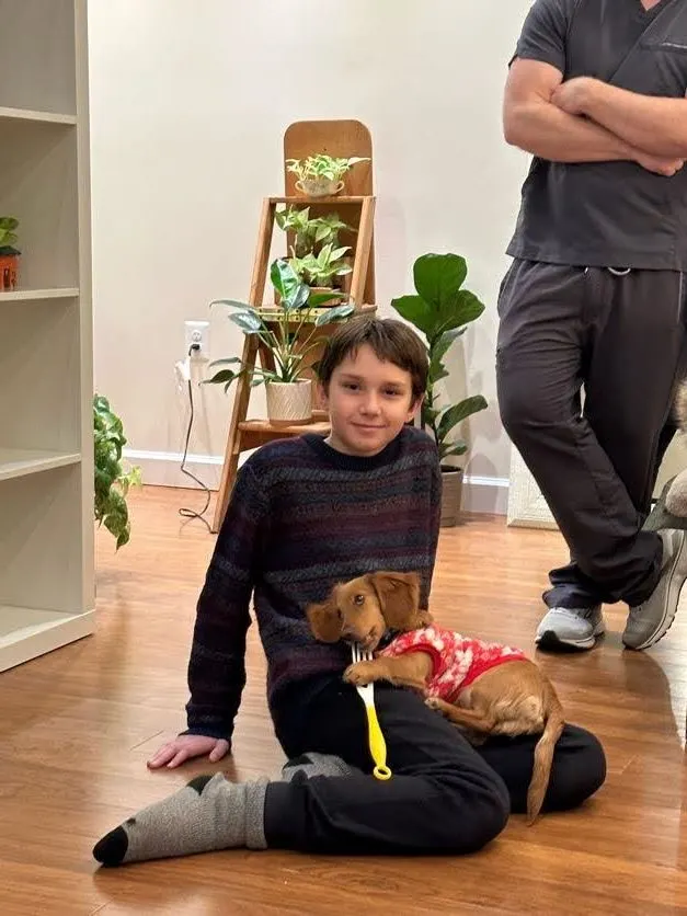 A young patient sitting with the office dog, Slinky